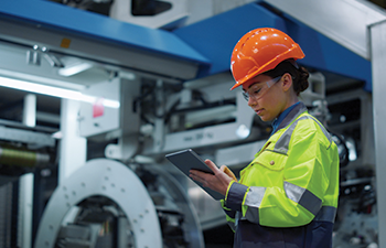A worker in a food and beverage facility checking a tablet during an inspection.
